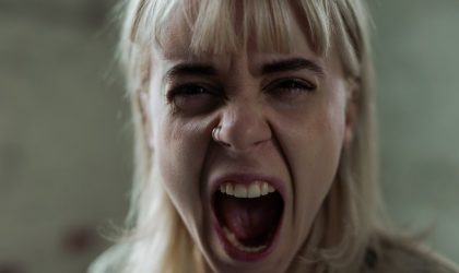Žena jako otvorenih usta, vidi se lice sa izraženom grimasom, vrišti.