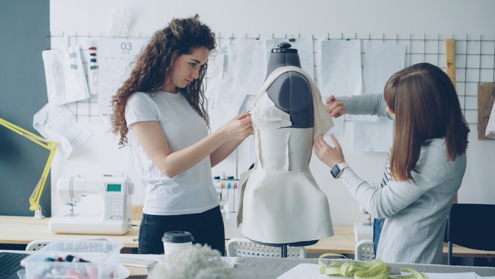 Dizajnerke u modnom studiju isprobavaju iskrojene šnitove na modelu.