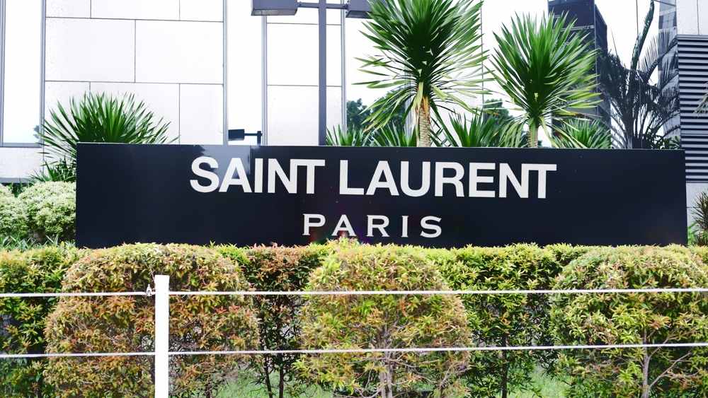 Crna tabla u zelenilu na kojoj piše Saint Laurent, Paris.